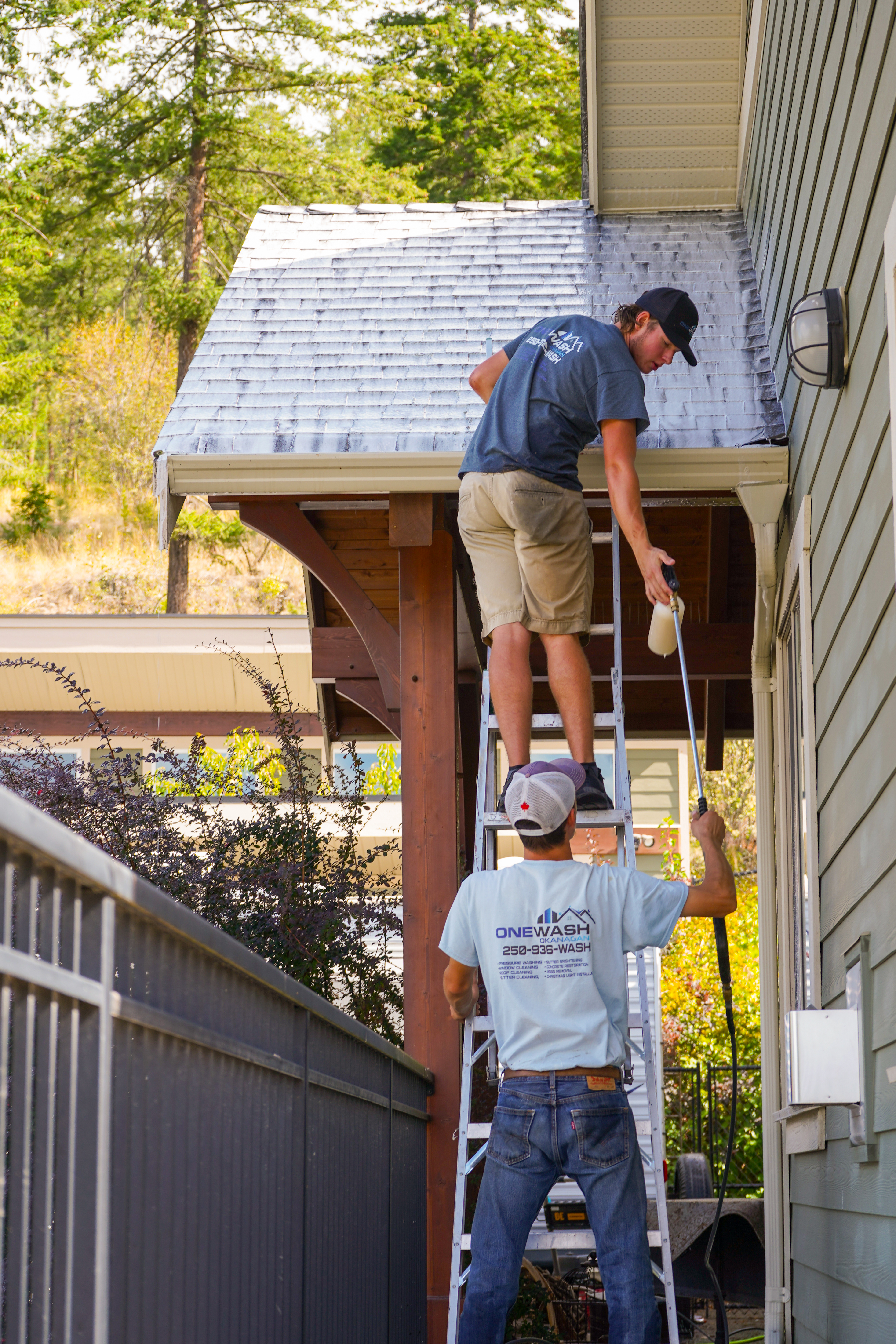 Two technicians cleaning a roofline